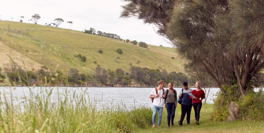 Students walk alongside a river at the Deakin Waurn Ponds Campus.