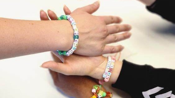 Three hands with friday friends bracelets on arms
