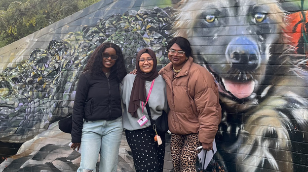 Three international students standing in front of a mural at the Melbourne Zoo