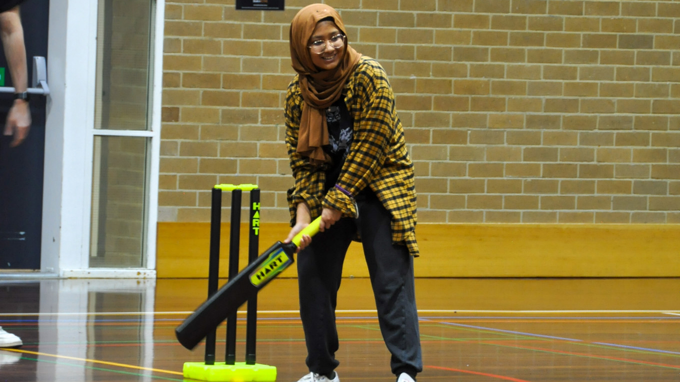 International student playing indoor cricket