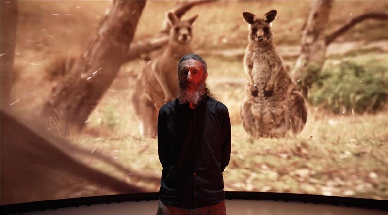 Don Driscoll stands in front of screen with two wallabies
