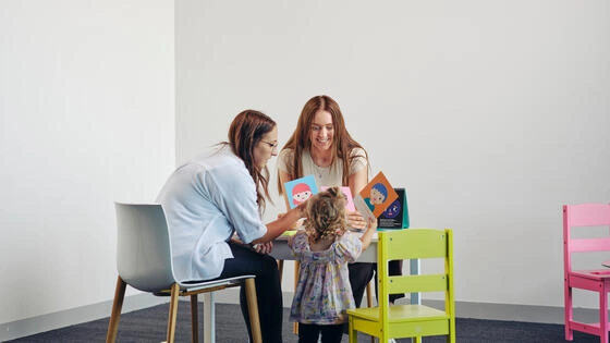 Two Deakin postgraduate therapeutic child play students interact with a child.