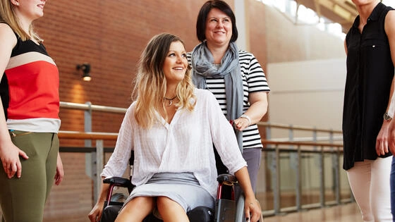 Deakin master of disability and inclusion students together outside, one student in a wheelchair smiling to those around her.