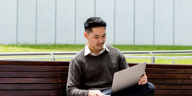 Man sitting on a bench with a laptop