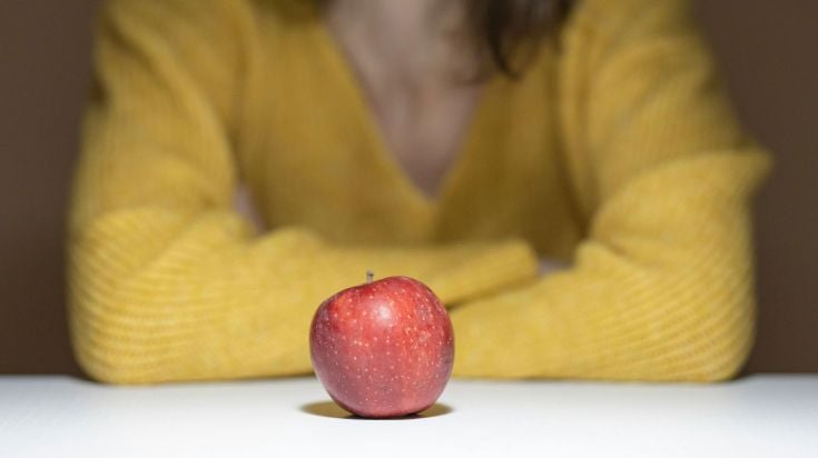 A person with an apple sitting on the table