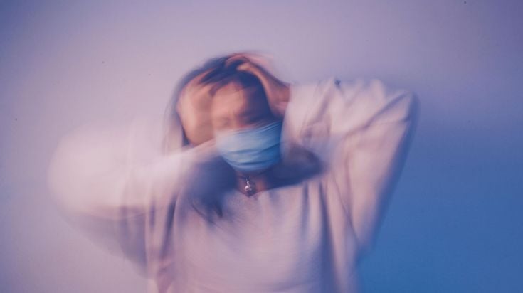 A woman in a mask shaking in a purple fog