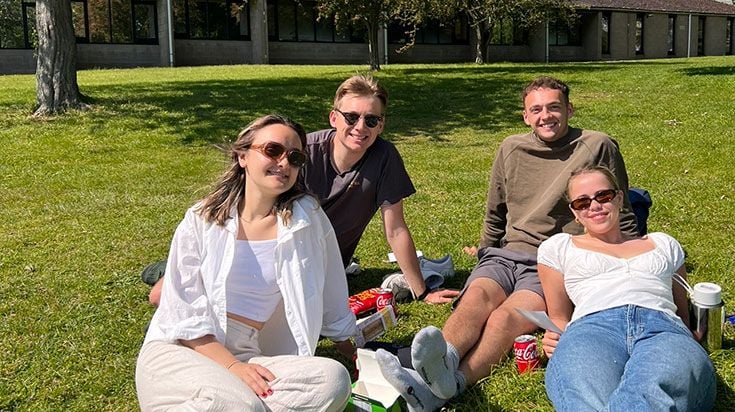 Students lounging on the lawn at UEA