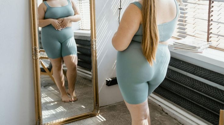 Woman looking at her body in the mirror