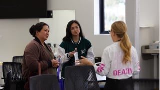 Two people talk to a staff member at Deakin Open Day.