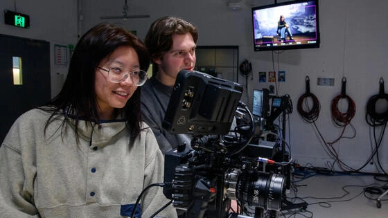 Two Deakin master of film and television students on set together operating cameras.