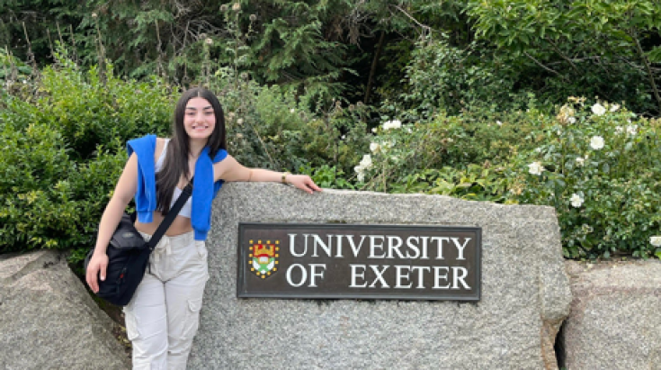 Student Shahad in front of the University of Exeter sign