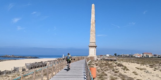 Person cycling down wooden boardwalk towards a lighthouse