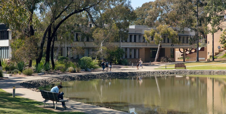 Students enjoy being outside at a lake in the sunlight at the Deakin Waurn Ponds Campus.