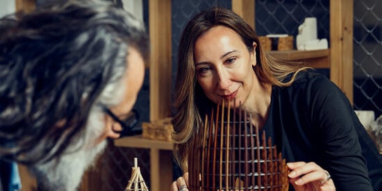 An architecture student inspects a wooden model. 