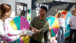 A person is handed a prize at the Spin to Win activation at Deakin Open Day.