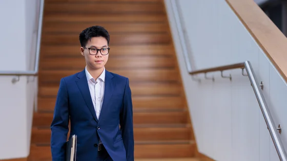 A student in a business suit walking down a staircase.