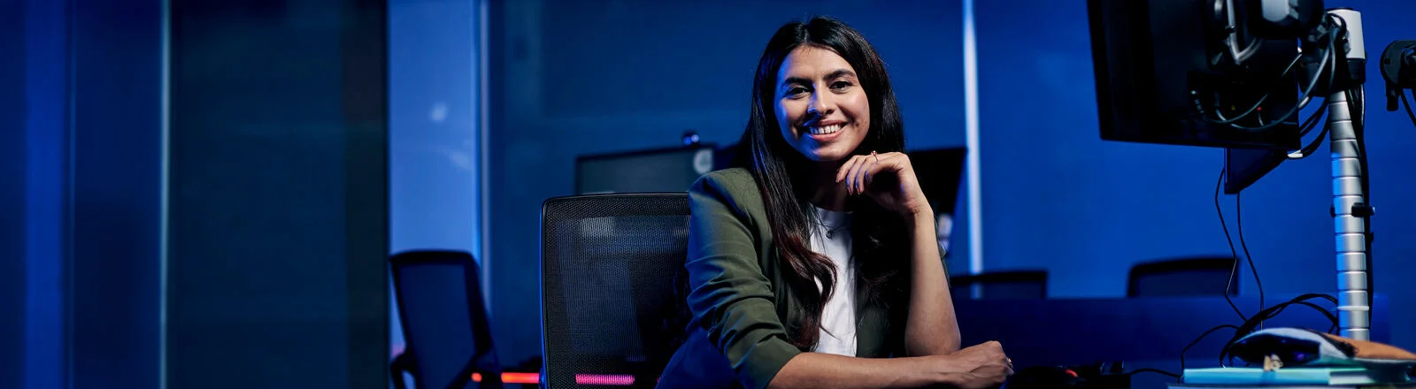 Deakin master of data science sitting at table with computer and smiling on campus.