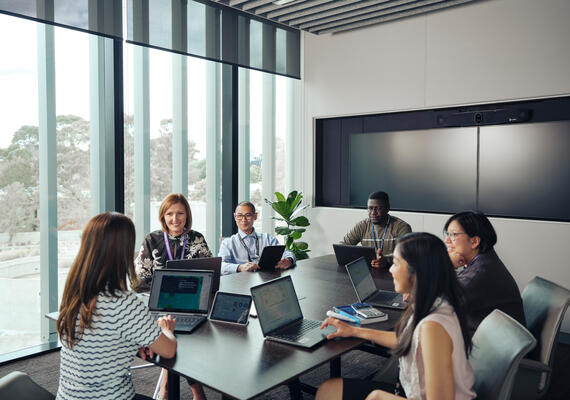 A group of Deakin health researchers sit at a table with open laptops conversing