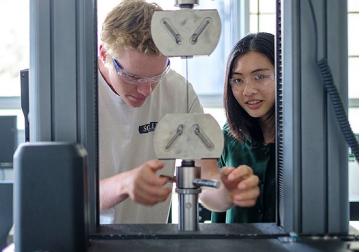 Two students use machine in engineering lab