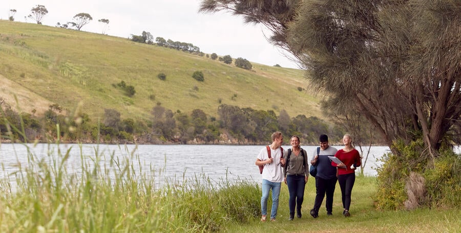 Students walk by a river at Deakin Warrnambool campus.
