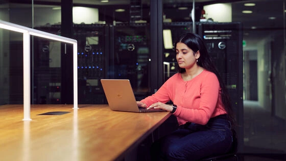 A Deakin postgraduate technology student works on a laptop.