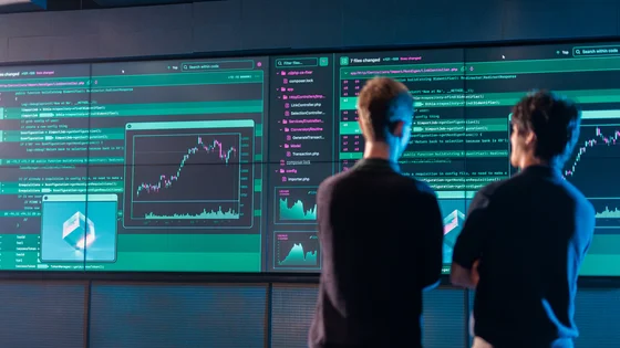 Two Deakin master of information systems students look at data on a large screen.