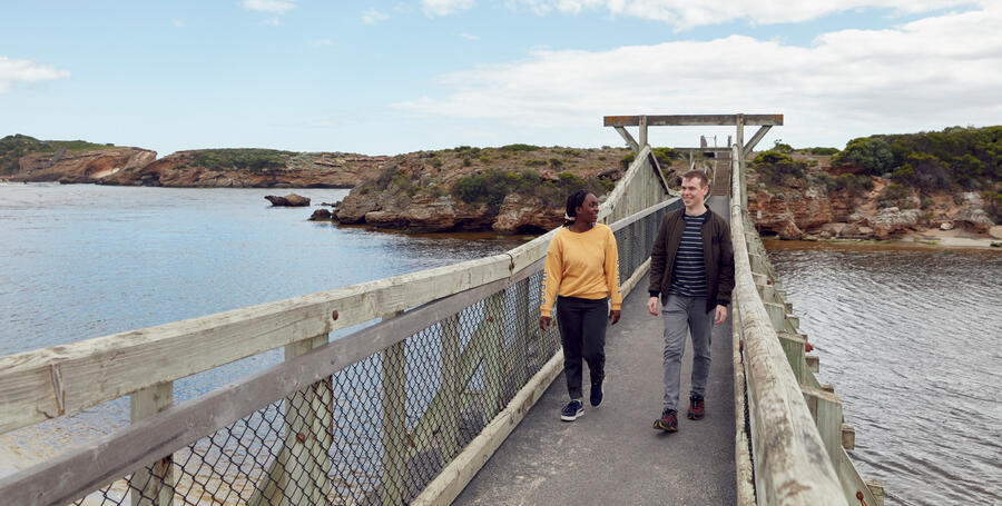 Two Deakin students walk along the pier at Deakin's Warrnambool Campus.