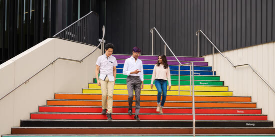 Three Deakin students walk down the rainbow stairs at the Melbourne Burwood Campus.