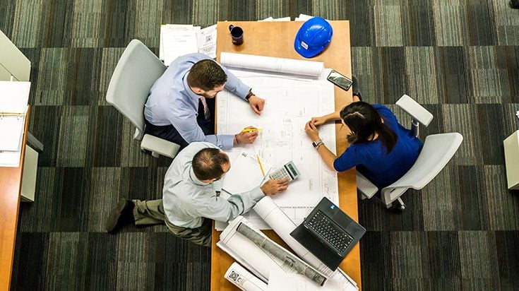 Group of engineers meeting a a table with plans