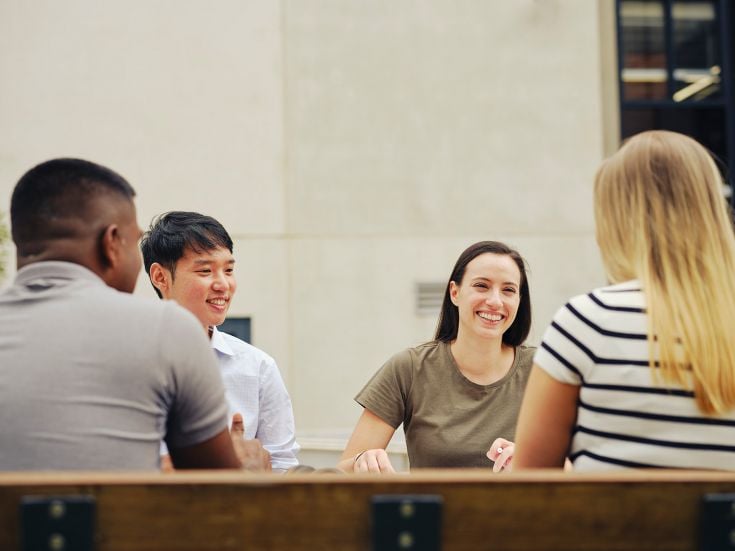 Three students sitting around table talking