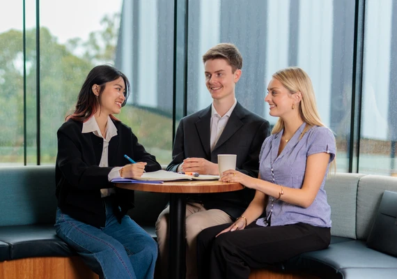 Three students in conversation sitting at a table 