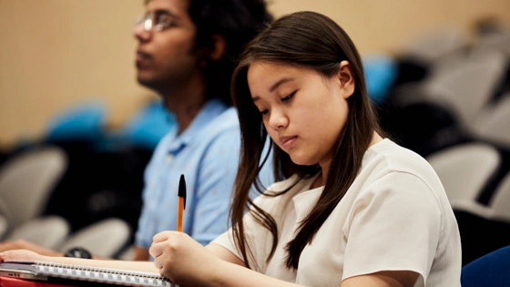 Student takes notes while sitting in a lecture