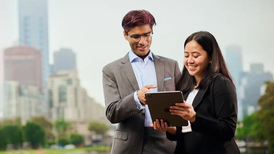 Two Deakin Master of Business students outside looking at a tablet.