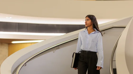 Deakin business student walks down a spiral staircase.