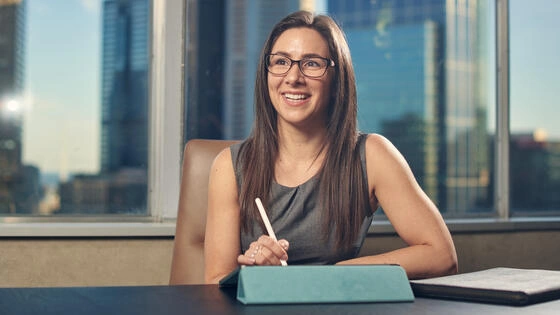 Deakin master of information technology management professional student sits at table smiling whilst working.