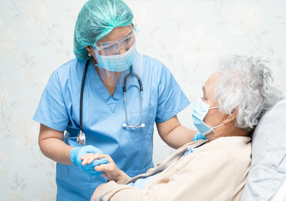 A nurse holds a patient's hand on bed 