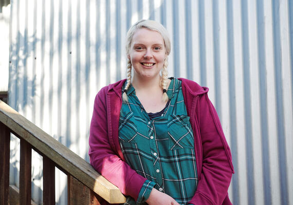 Environment student Chloe Daws leans against a staircase outdoors.