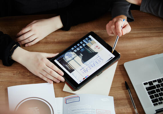 Aerial shot of two students looking at a tablet, surrounded by study materials.