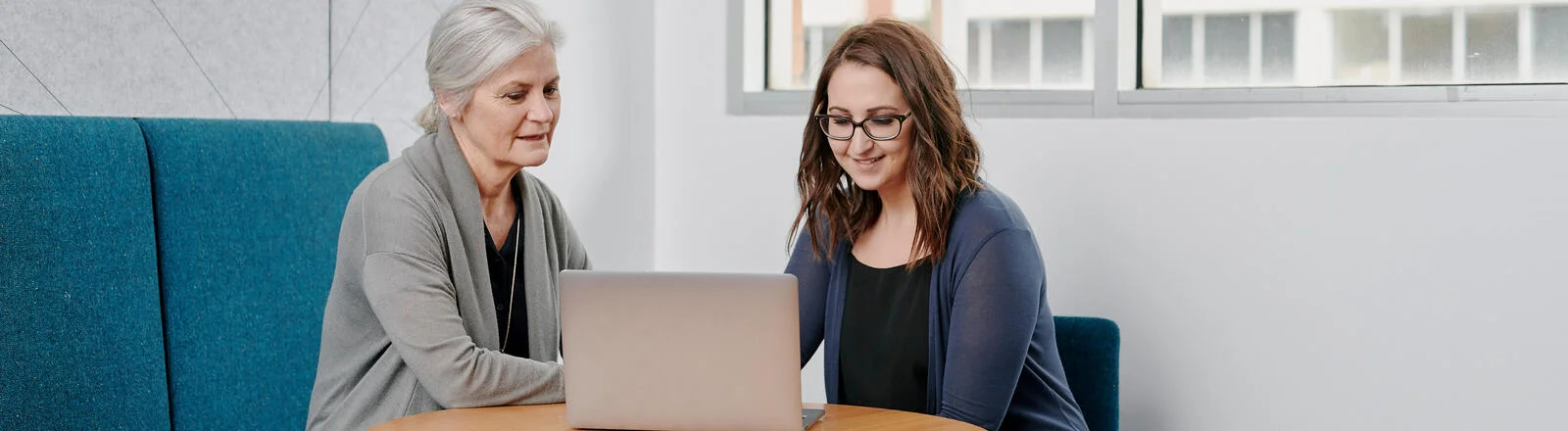 Two Deakin postgraduate public health students sit at a desk looking at a laptop.