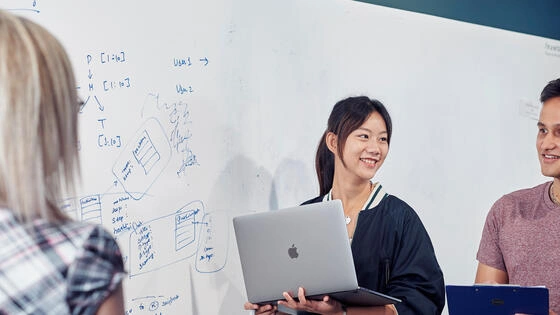 Deakin bachelor of cyber security students stand and work together on campus.