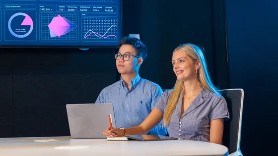Two students reviewing data on a large screen.