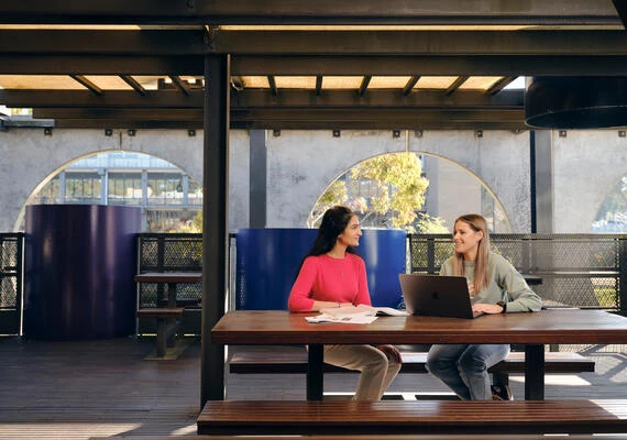 Two Deakin students sitting and talking at Geelong Waurn Ponds Campus