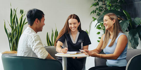 Three psychology students talking while taking notes
