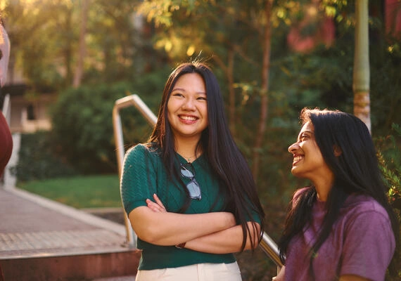 Two Deakin international students socialise and smile at the camera