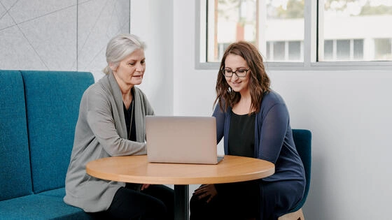 Two Deakin postgraduate public health students sit at a desk looking at a laptop.