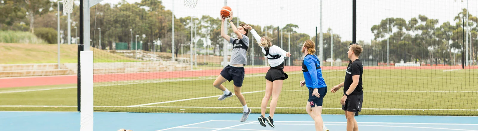 A Deakin postgraduate sport performance analysis student watches a group of students play basketball. 