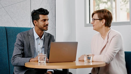 Two Deakin diploma of health management students sit at a table and talk.
