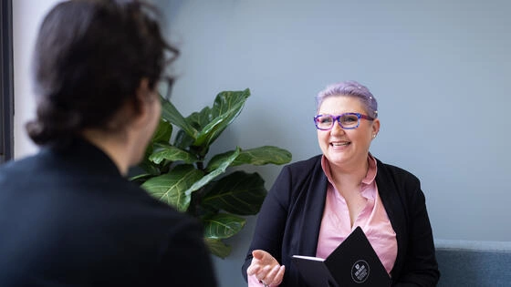 Deakin master of human resource management student talks to someone sitting across from them, smiling.