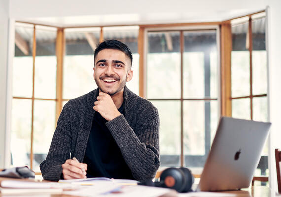 Deakin online student smiles while using laptop.