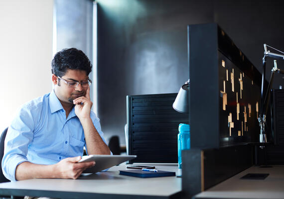 Office worker looking at a tablet at their desk